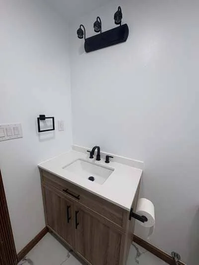 White quartz vanity with wood cabinet, matte black faucet and mirror fixtures in bathroom