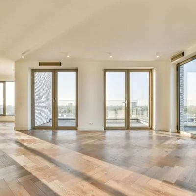 Open residential space with recessed ceiling lights, bronze-framed glass doors, wood and concrete flooring