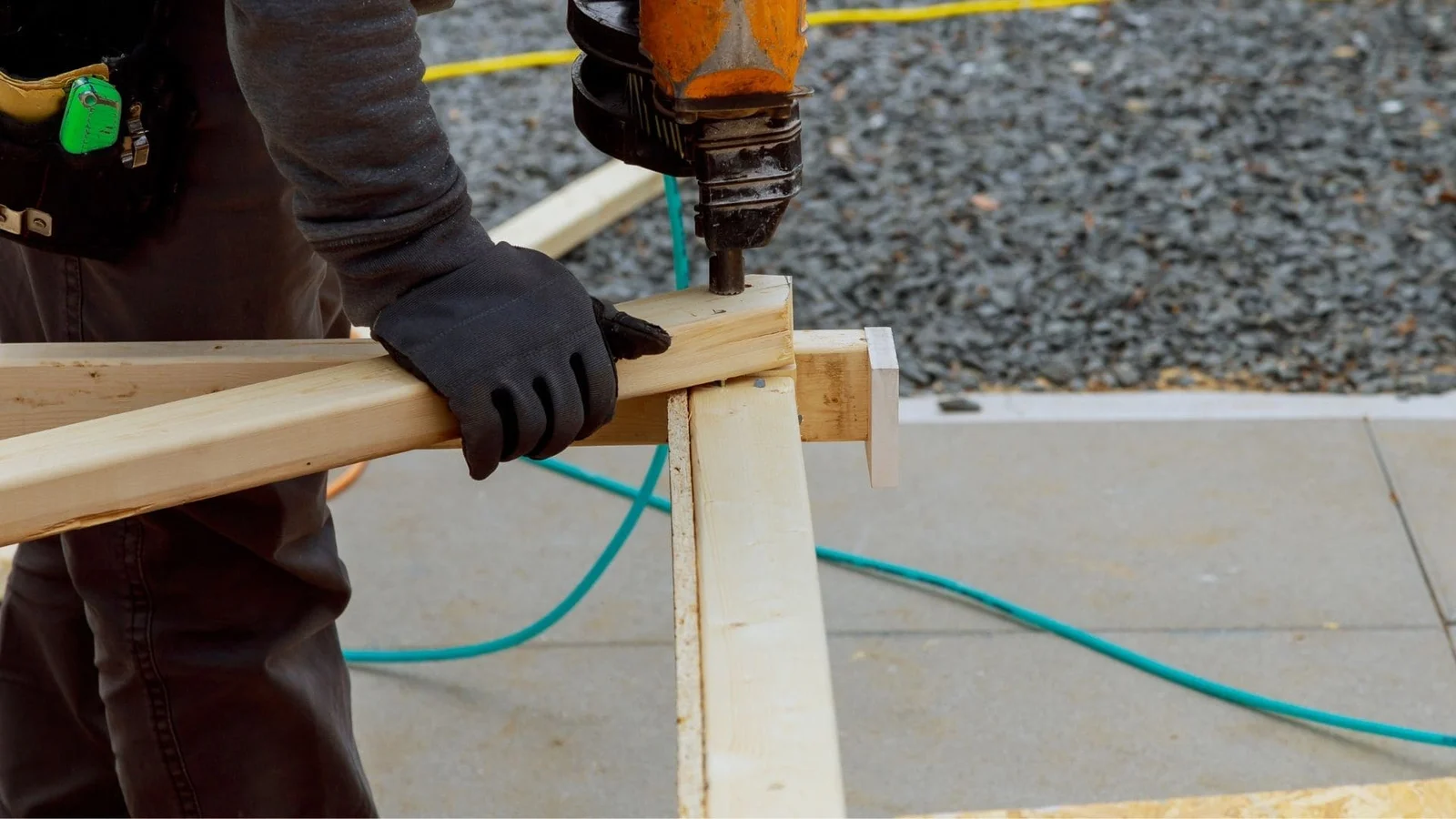 Roof framing installation with dimensional lumber, fasteners, and power drill on concrete substrate