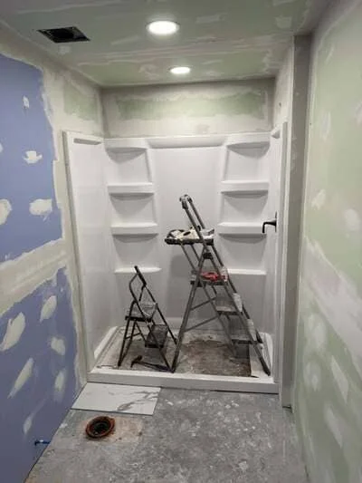 Walk-in shower with white subway tile, built-in shelves, and recessed lighting during installation